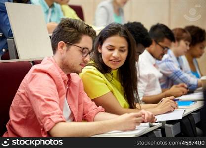 education, high school, university, learning and people concept - group of international students with notebooks writing at lecture