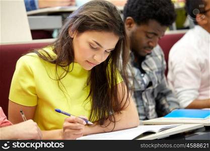 education, high school, university, learning and people concept - group of international students with notebooks writing at lecture