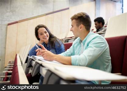 education, high school, university, learning and people concept - group of international students with notebooks talking at lecture hall