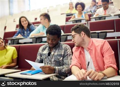 education, high school, university, learning and people concept - group of international students with test in lecture hall
