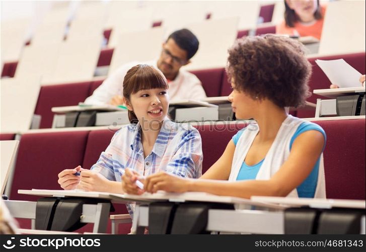 education, high school, university, learning and people concept - group of international students talking in lecture hall
