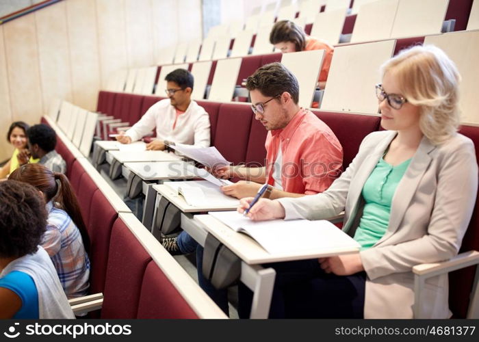 education, high school, university, learning and people concept - group of international students writing test at lecture hall