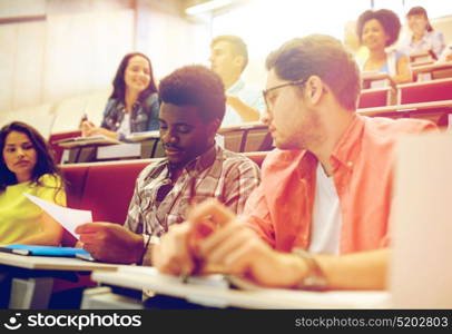 education, high school, university, learning and people concept - group of international students with test in lecture hall. group of international students in lecture hall