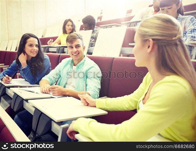 education, high school, university, learning and people concept - group of international students with notebooks talking at lecture hall. group of students with notebooks at lecture hall