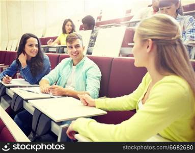education, high school, university, learning and people concept - group of international students with notebooks talking at lecture hall. group of students with notebooks at lecture hall