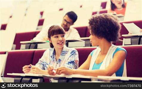 education, high school, university, learning and people concept - group of international students talking in lecture hall. group of students talking in lecture hall