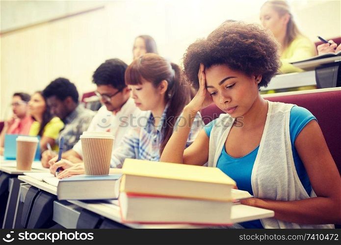 education, high school, university, learning and people concept - group of international students with notebooks and coffee writing test in lecture hall. group of students with coffee writing on lecture
