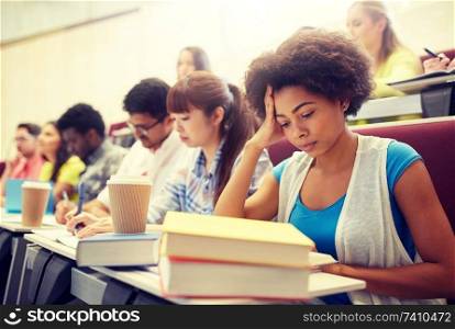 education, high school, university, learning and people concept - group of international students with notebooks and coffee writing test in lecture hall. group of students with coffee writing on lecture