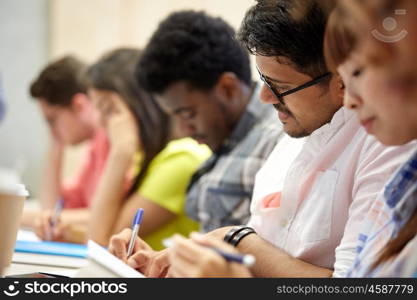 education, high school, university, learning and people concept - group of international students writing at lecture