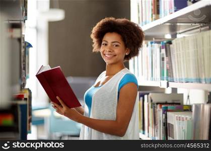 education, high school, university, learning and people concept - happy smiling african american student girl reading book at library