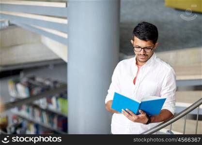 education, high school, university, learning and people concept - hindu student boy or young man reading book on stairs at library