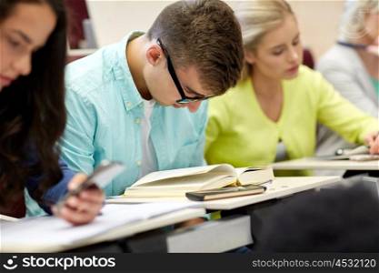 education, high school, university, learning and people concept - male student in glasses reading book at lecture