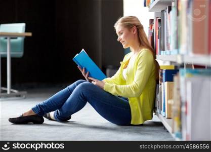 education, high school, university, learning and people concept - smiling student girl reading book sitting on floor at library