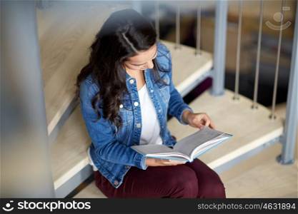education, high school, university, learning and people concept - smiling student girl reading book sitting on stairs