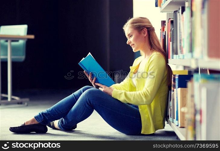 education, high school, university, learning and people concept - smiling student girl reading book sitting on floor at library. high school student girl reading book at library