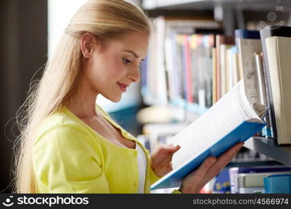 education, high school, university, learning and people concept - smiling student girl reading book at library