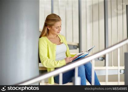 education, high school, university, learning and people concept - smiling young woman or student girl reading book sitting on stairs