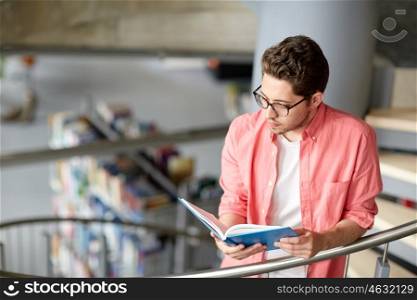 education, high school, university, learning and people concept - student boy or young man reading book on stairs at library