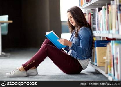 education, high school, university, learning and people concept - student girl reading book sitting on floor at library