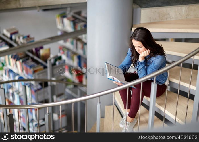 education, high school, university, learning and people concept - student girl reading book sitting on stairs at library