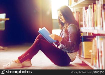 education, high school, university, learning and people concept - student girl reading book sitting on floor at library. high school student girl reading book at library