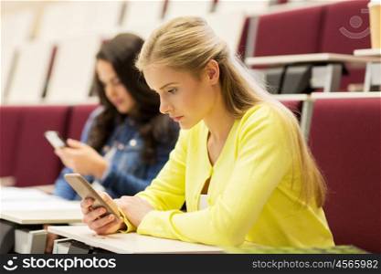 education, high school, university, learning and people concept - student girls with smartphones on lecture