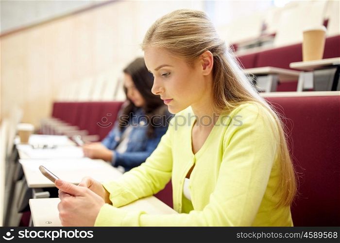 education, high school, university, learning and people concept - student girls with smartphones on lecture