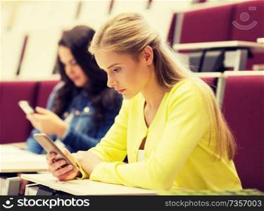 education, high school, university, learning and people concept - student girls with smartphones on lecture. student girls with smartphones on lecture