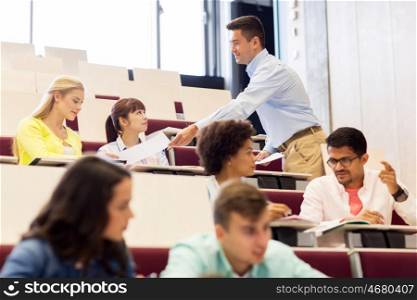 education, high school, university, learning and people concept - teacher giving test to students on lecture