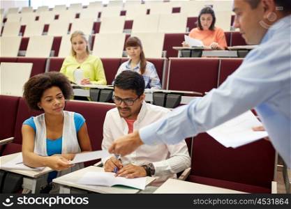 education, high school, university, learning and people concept - teacher giving tests to students at lecture