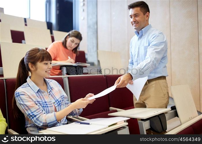 education, high school, university, learning and people concept - teacher giving tests to students at lecture