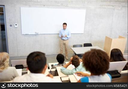 education, high school, university, teaching and people concept - group of international students and teacher with papers standing at white board at lecture