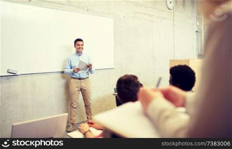 education, high school, university, teaching and people concept - group of international students and teacher with papers standing at white board at lecture. group of students and teacher at lecture