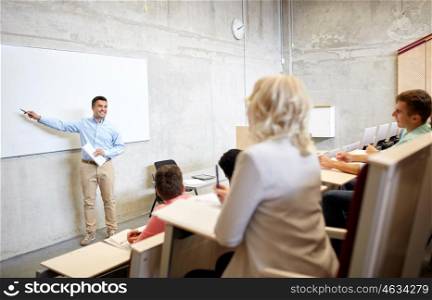 education, high school, university, teaching and people concept - group of students and teacher with marker standing at white board at lecture