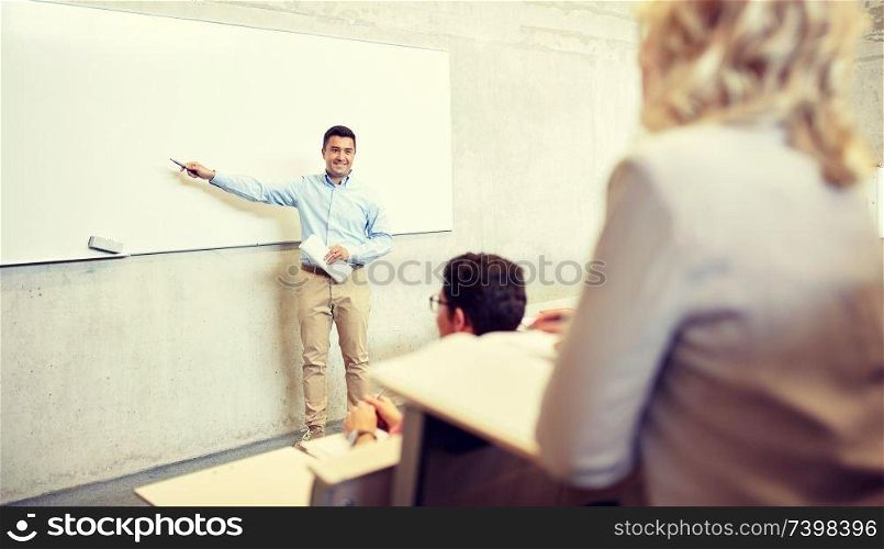 education, high school, university, teaching and people concept - group of students and teacher with marker standing at white board at lecture. group of students and teacher at lecture