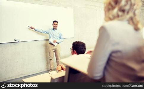 education, high school, university, teaching and people concept - group of students and teacher with marker standing at white board at lecture. group of students and teacher at lecture