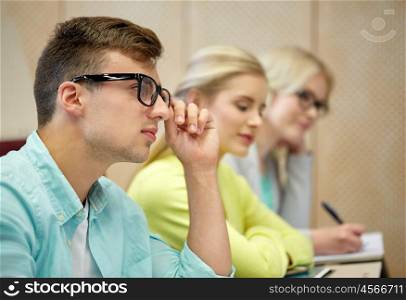 education, high school, university, vision and people concept - young man in eyeglasses with group of students at lecture