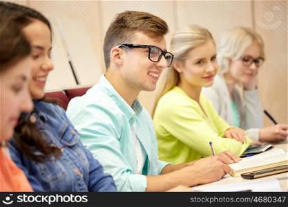 education, high school, university, vision and people concept - young man in eyeglasses with group of students at lecture