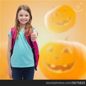 education, holidays, childhood, gesture and people concept - smiling little girl with backpack showing thumbs up over halloween pumpkins background
