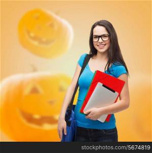 education, holidays, school and people concept - smiling student girl in glasses with books and bag over halloween pumpkins background