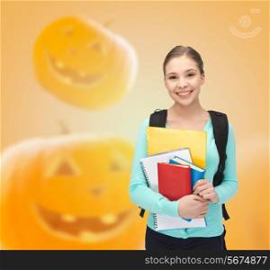 education, holidays, school and people concept - smiling student girl with books and backpack over halloween pumpkins background