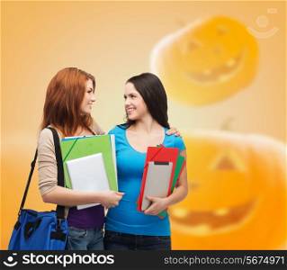 education, holidays, school, friendship and people concept - smiling student girls with books and bag over halloween pumpkins background