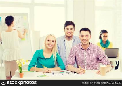 education, interior design and office concept - smiling interior designers with color samples and blueprint in office