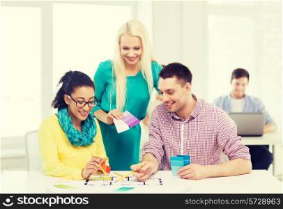 education, interior design and office concept - smiling interior designers with color samples and blueprint in office
