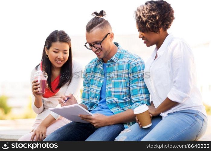 education, international and people concept - group of happy exchange students with notebook and takeaway drinks outdoors. students with notebook and takeaway drinks