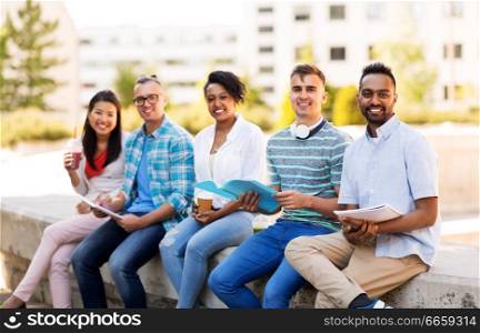 education, international and people concept - group of happy exchange students with notebook and takeaway drinks outdoors. students with notebook and takeaway drinks