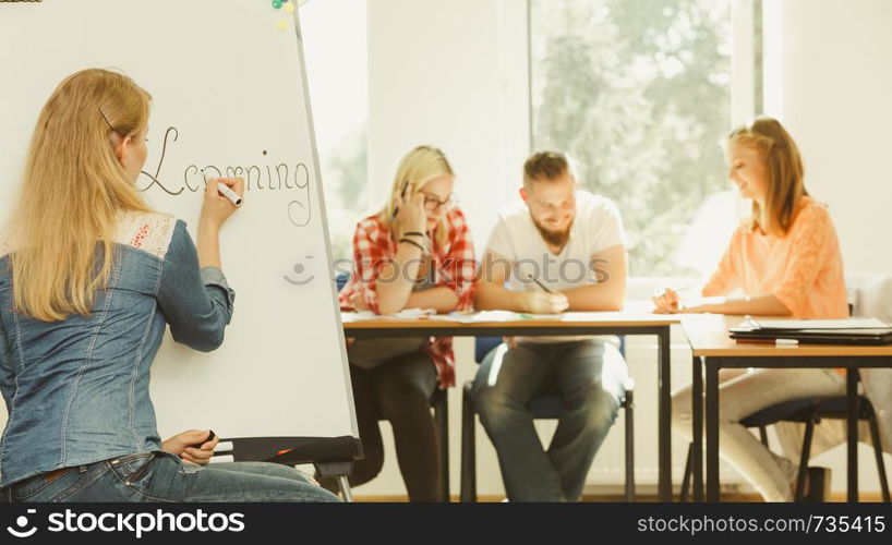 Education, knowledge, wisdom and learn new things concept - student girl writing Learning word on whiteboard in front of students her group mates in classroom. Student girl writting Learning word on whiteboard