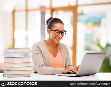 education, learning and business concept - african american female student with laptop computer and books over school or office background. female student with laptop computer and books