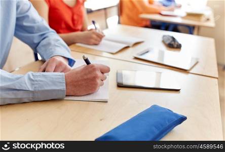 education, learning and people concept - close up of student boy with notebook and book writing school test