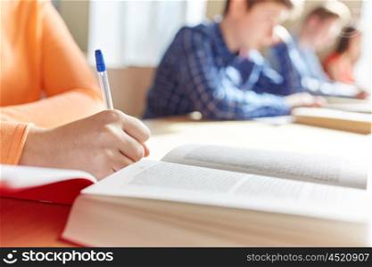education, learning and people concept - close up of student girl hand with book writing school test